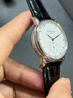 Patek Philippe watch side view with black leather strap and white dial, silver case profile