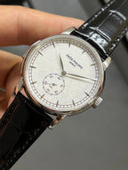 Patek Philippe watch front view with black leather strap and white dial with subdial layout