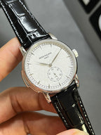 Patek Philippe watch front angled view with black leather strap and white dial, silver bezel