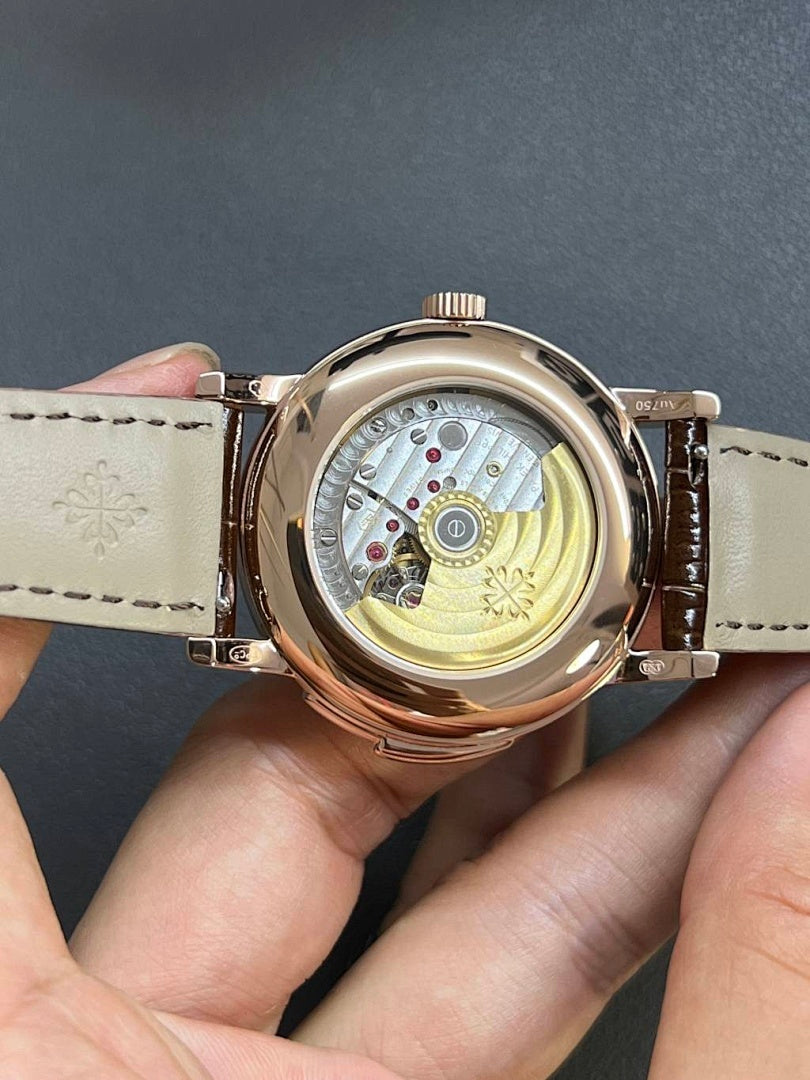 Round wristwatch open caseback showing gold-toned movement; brown leather strap