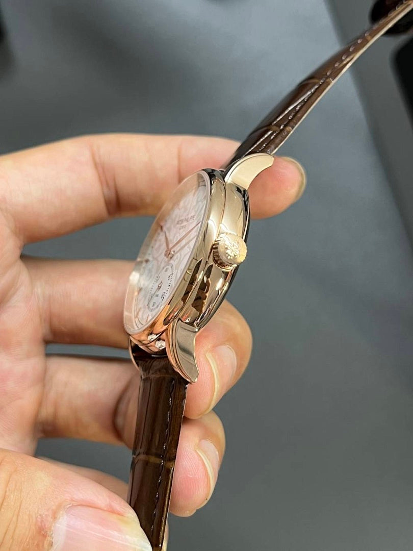 Round wristwatch side profile with crown on gold-tone case; brown leather strap