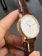 Round wristwatch front with white dial, gold-tone bezel, brown leather strap