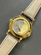 Patek Philippe watch caseback on brown leather strap, gold-tone back and dial
