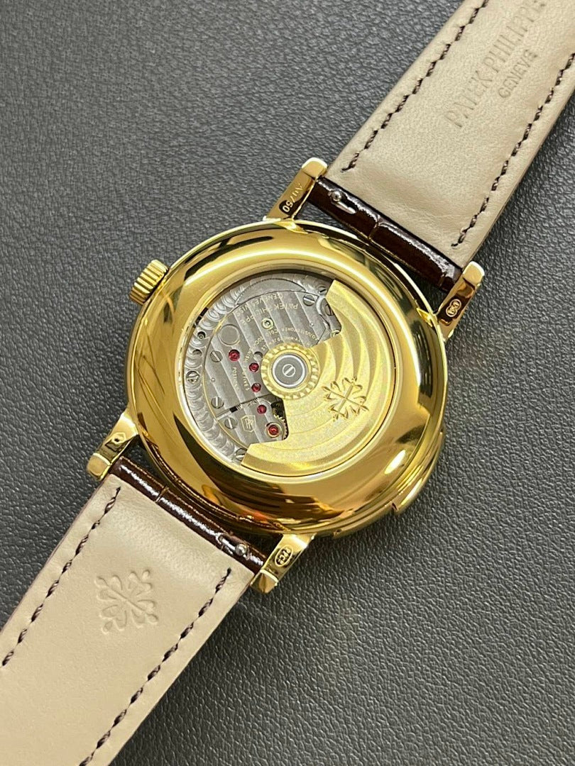 Patek Philippe watch caseback on brown leather strap, gold-tone back and dial