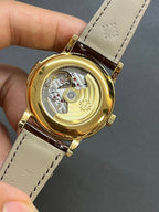 Patek Philippe watch caseback view on brown leather strap, gold-tone surround