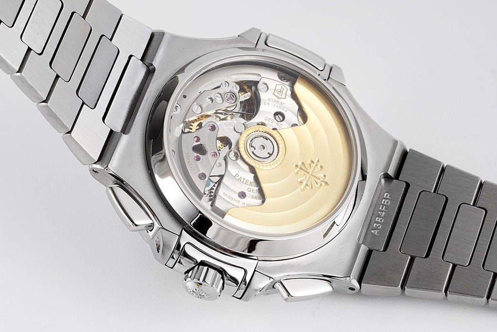 Open caseback view showing watch movement, silver case and stainless bracelet links.