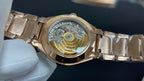 Gold-tone wristwatch with visible mechanical movement through clear caseback