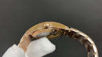 Gold-tone wristwatch caseback close-up with crown and metal link bracelet