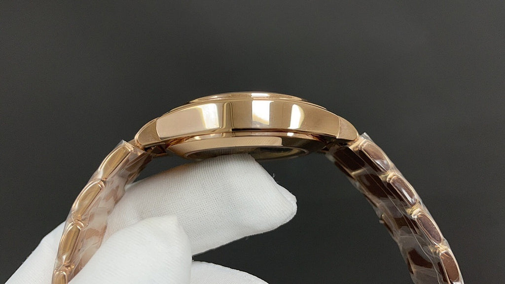 Gold-tone Patek Philippe watch case with curved bezel close-up on a glove