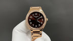 Gold-tone Patek Philippe watch with brown dial and diamond bezel on a glove