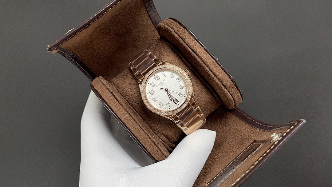 Patek Philippe watch in brown presentation case, white dial on metal bracelet.