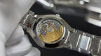 Patek Philippe watch with visible mechanical movement on silver metal case.