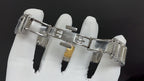 Steel watch bracelet clasp and case back, held in white-gloved hands