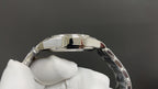 Polished metal watch case profile with curved bezel, held in white gloves