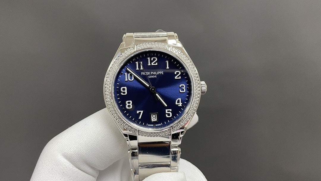 Silver wristwatch with blue dial, diamond bezel, and metal bracelet on glove hand