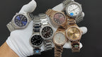 Group of luxury wristwatches with blue, black, brown, and silver dials on gloves