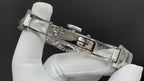 Silver metal wristwatch bracelet with clasp held in white gloves