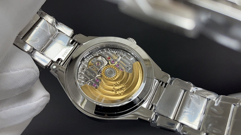 Skeleton-style wristwatch with gold-toned interior and metal bracelet on glove hand