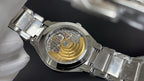 Skeleton-style wristwatch with gold-toned interior and metal bracelet on glove hand