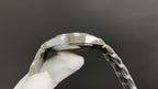 Silver wristwatch case top and bezel with clear strap links on glove hand
