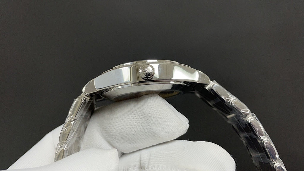 Silver wristwatch case with crown and bracelet links on glove hand