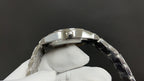Silver wristwatch case with crown and bracelet links on glove hand