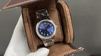 Silver wristwatch with blue dial on brown suede watch box