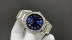 Blue-dial silver wristwatch angled view with diamond bezel on metal bracelet