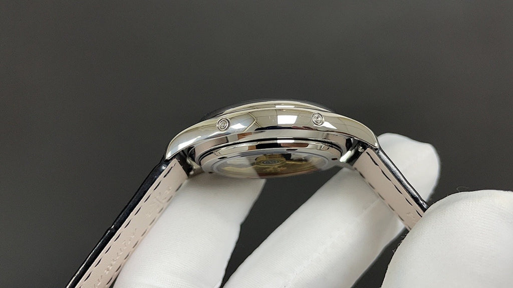 Patek Philippe wristwatch crown and case top, glossy silver-tone finish, black strap