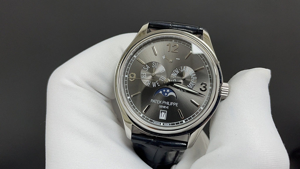 Patek Philippe wristwatch with dark dial, Roman numerals, black leather strap, silver case