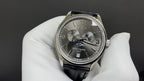Patek Philippe wristwatch with dark dial, Roman numerals, black leather strap, silver case
