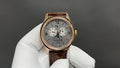 Gold-tone wristwatch with silver dial, brown leather strap, three subdials