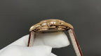 Gold-tone wristwatch case back on brown leather strap