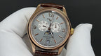 Gold-tone wristwatch with silver dial and brown leather strap, roman numerals