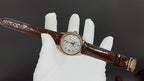 Brown leather strap wristwatch on glove, gold-tone case and light dial