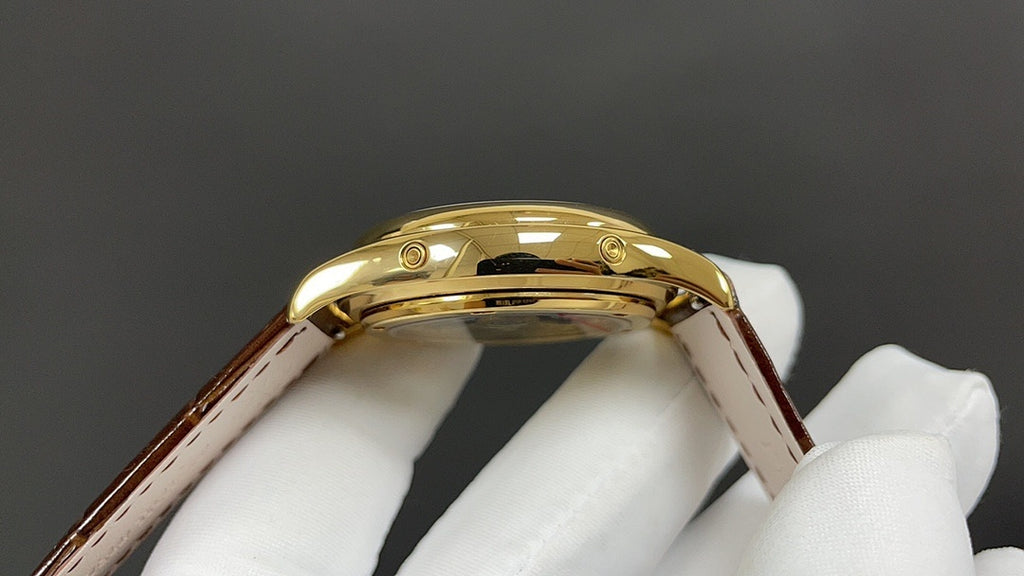 Patek Philippe watch gold crown and case profile with brown leather strap.