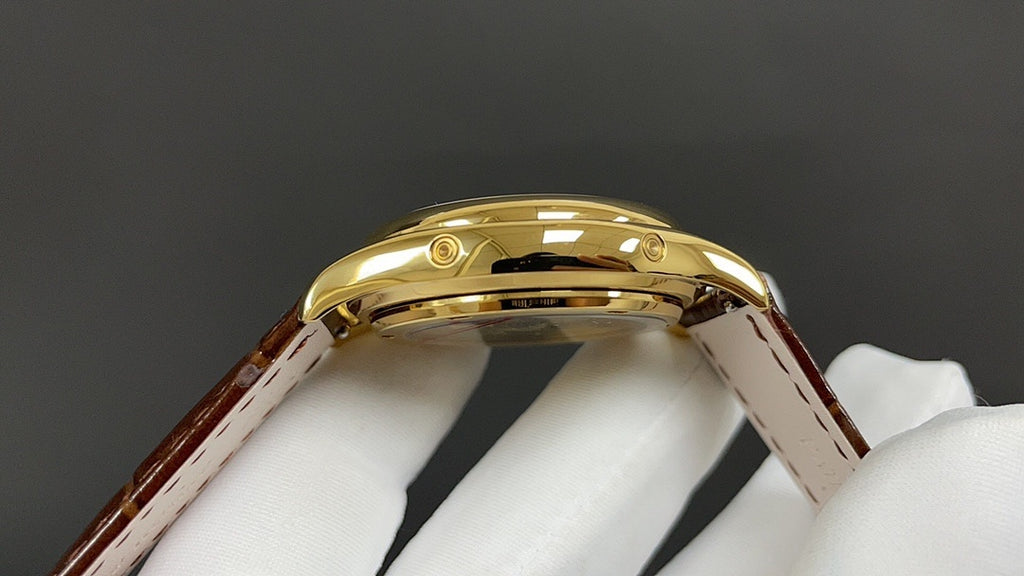 Patek Philippe wristwatch top view, polished gold case and curved bezel, brown strap