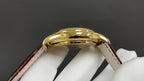 Patek Philippe wristwatch top view, polished gold case and curved bezel, brown strap