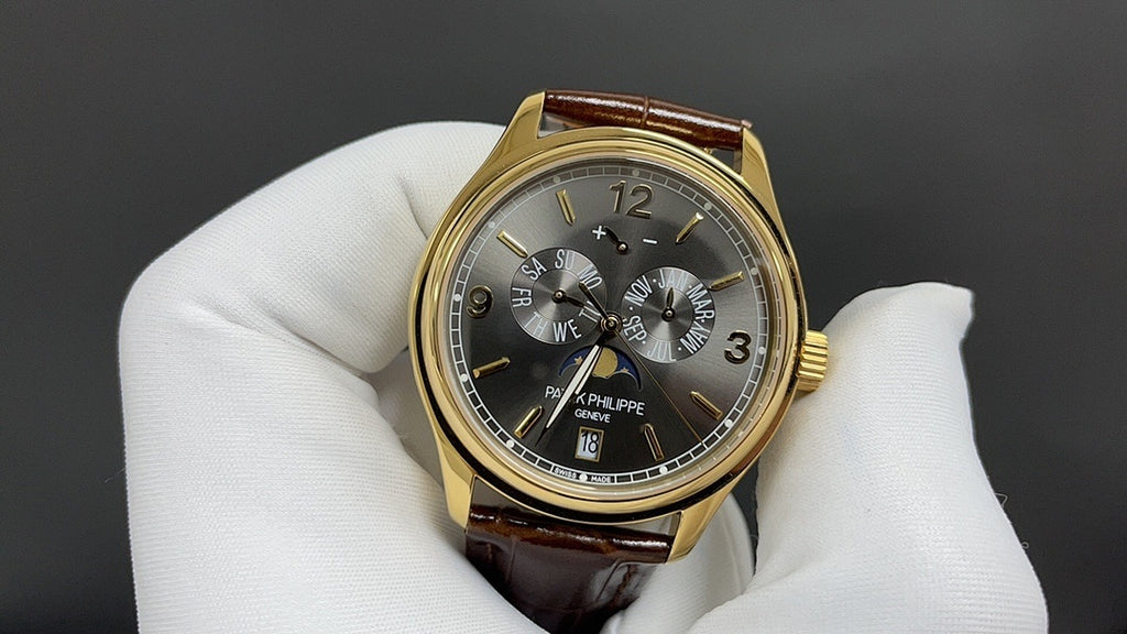 Patek Philippe wristwatch dark dial with three subdials, gold bezel, brown leather strap