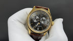 Patek Philippe wristwatch dark dial with three subdials, gold bezel, brown leather strap
