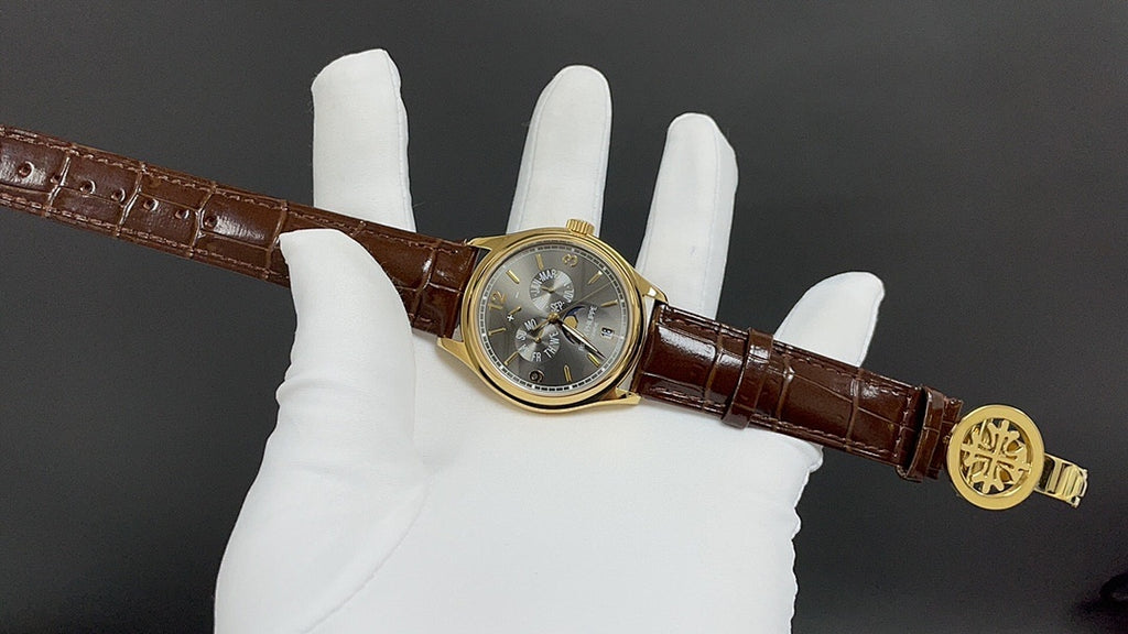 Patek Philippe wristwatch on hand, gold buckle, brown leather strap, round dark dial