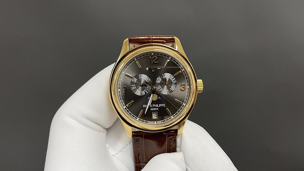 Patek Philippe wristwatch front view, dark dial with subdials, gold bezel, brown leather strap