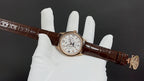 Patek Philippe wristwatch on brown leather strap, gold-tone case, side view