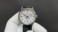 Patek Philippe watch with white dial and black leather strap, silver case with crown