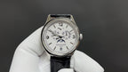 Patek Philippe watch with white dial and black leather strap, silver bezel and hands