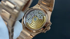 Patek Philippe watch case with exposed mechanical movement and gold-toned inner parts.