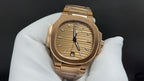 Patek Philippe gold-tone wristwatch with textured champagne dial and black hands.