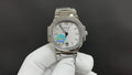 Silver metal wristwatch with jeweled bezel, white dial, and rainbow center motif