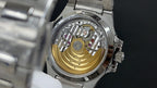 Skeleton view of a silver wristwatch with visible movement and gold-toned base