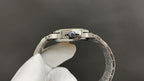 Silver metal wristwatch with blue gemstone detail on the bezel